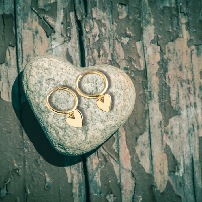 Ari Love Heart Earrings in gold on a heart rock