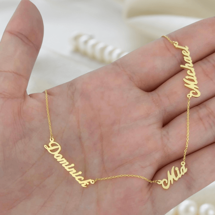 A persona holding the Adele Multiple Name Neckalce in gold with 3 names