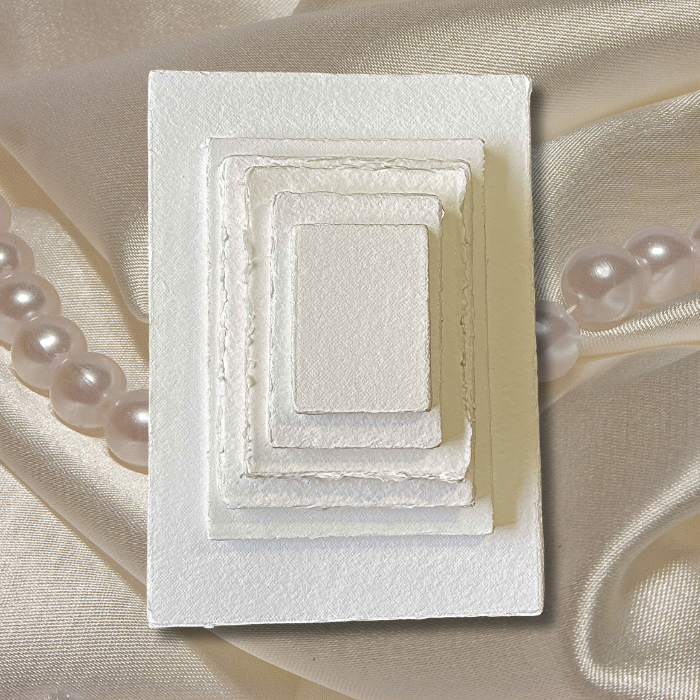 300 gsm handmade paper in different sizes stacked on a cream satin background