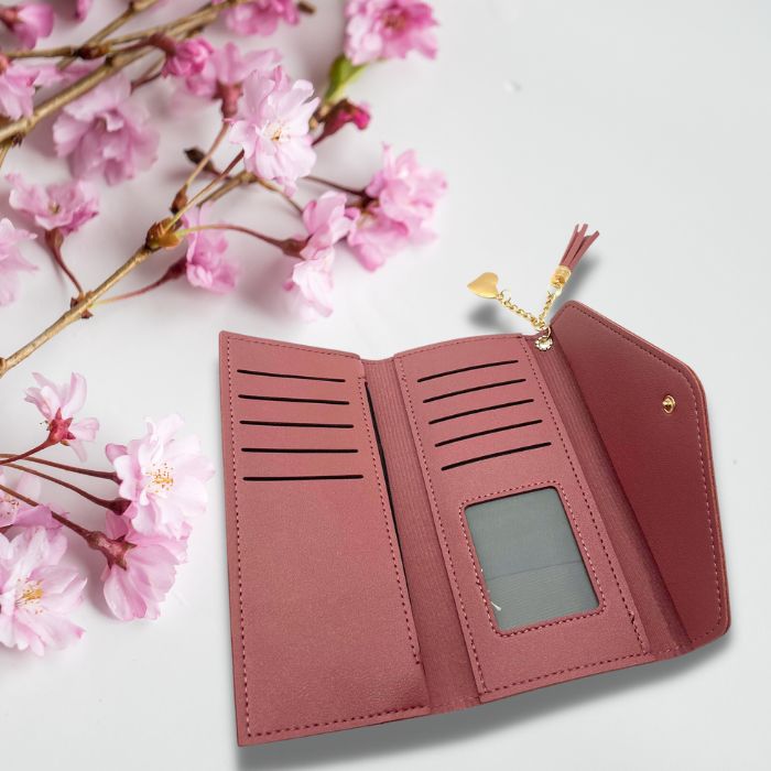 Open fuchsia leather wallet with pink flowers in background. 