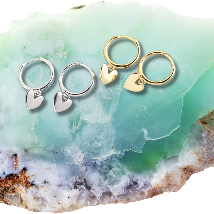 Ari Love Heart Earrings in gold and silver on a green rock.