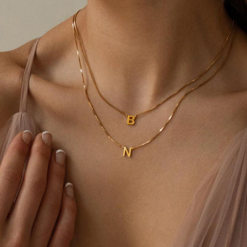 A woman wearing the Delaney custom necklace initials in letters B and N in gold
