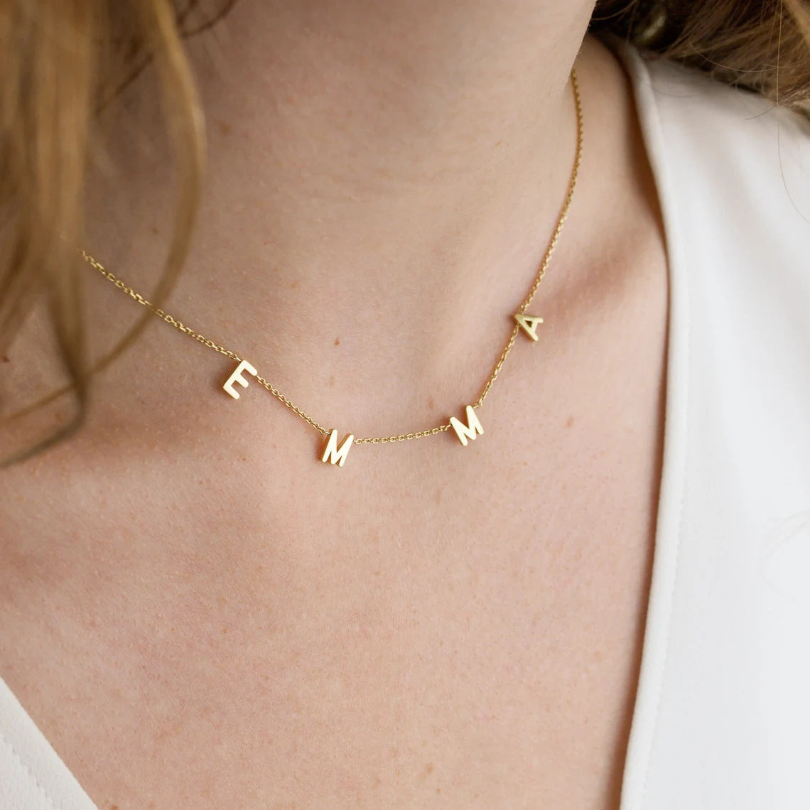 A woman wearing Amara letter necklace in gold with initials E M M A.